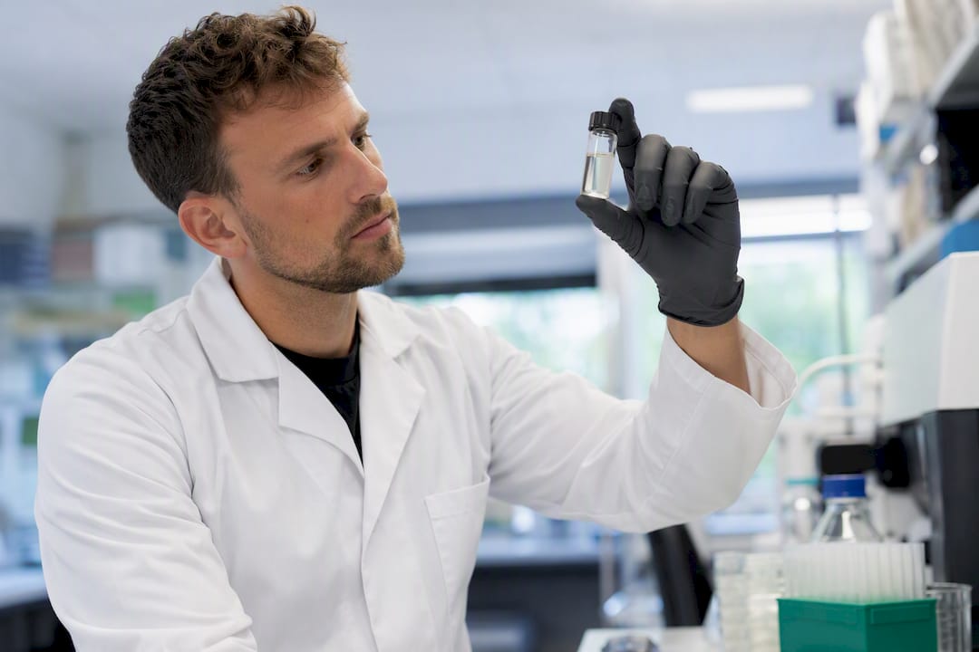 Gloved hand inspecting peptide vial discoloration