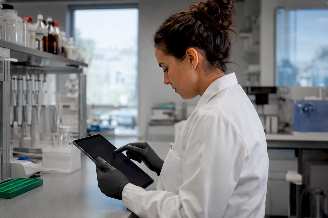 Gloved hands accessing supplier database on tablet